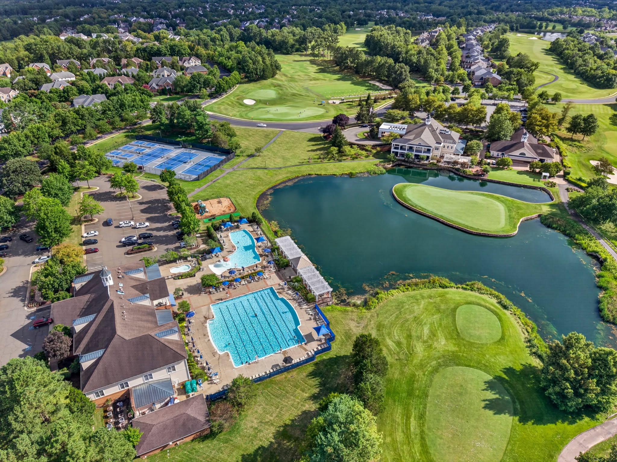 High aerial view of community pools, a clubhouse and a golf course