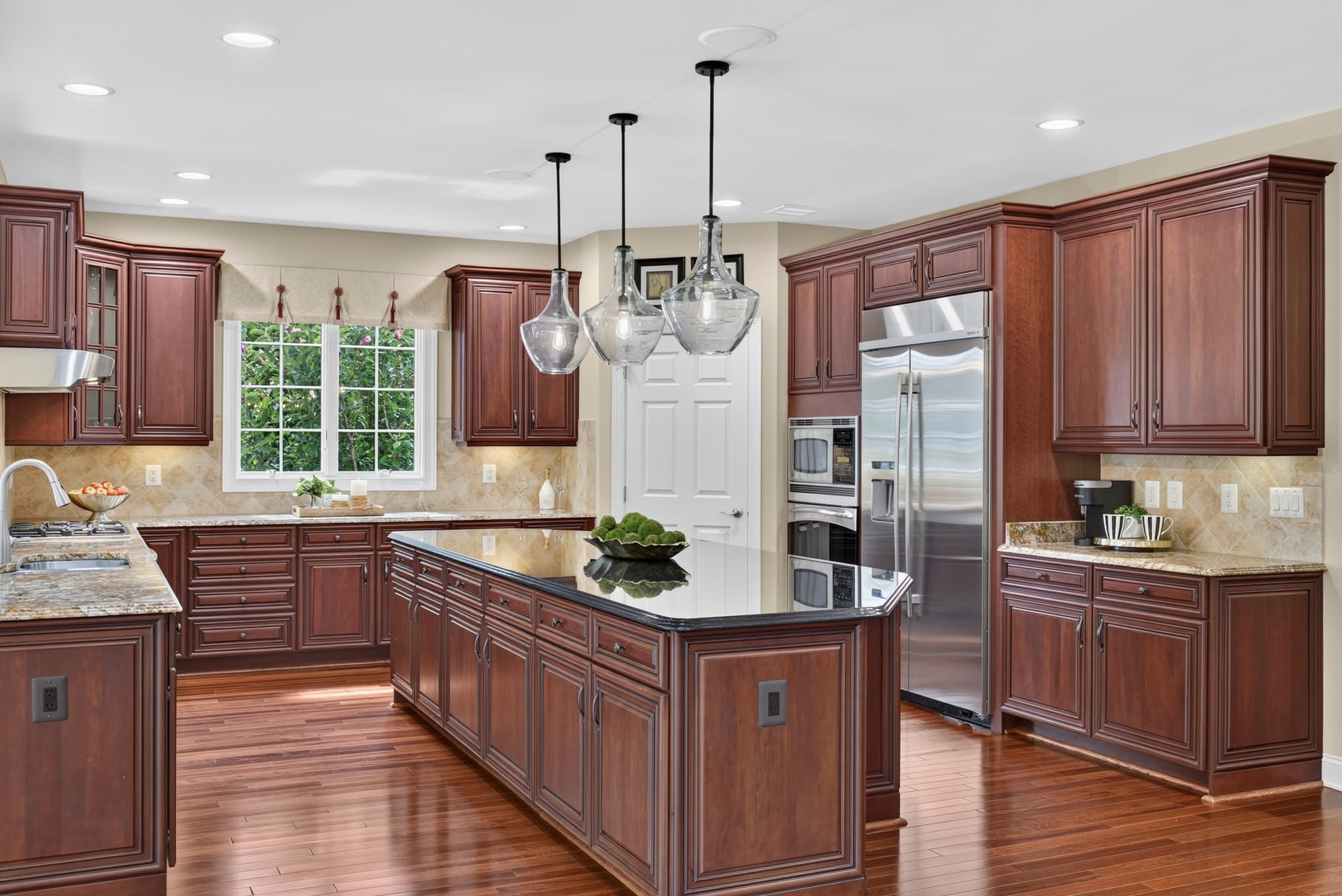 Kitchen with cherry cabinets, a granite island and glass pendant lights