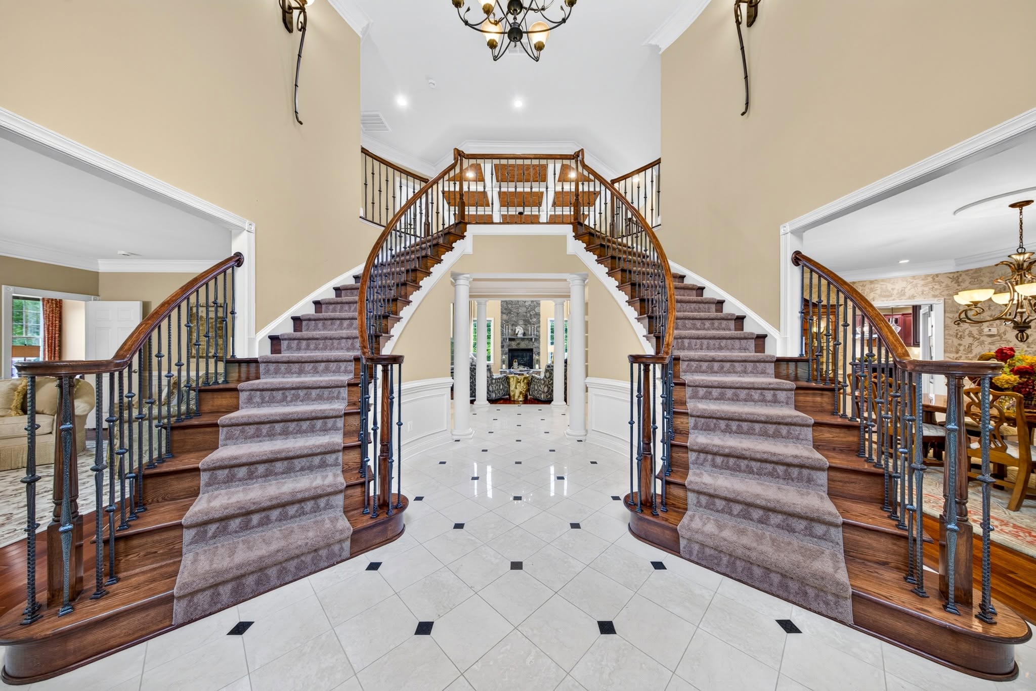 Grand foyer with a curved double staircase and a tall arched window